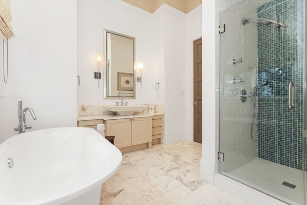 A modern bathroom with a freestanding bathtub, a glass-enclosed shower, and a vanity with a large mirror.