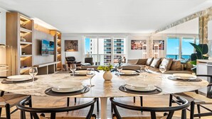A modern dining area with a marble table, black chairs, and a central vase.