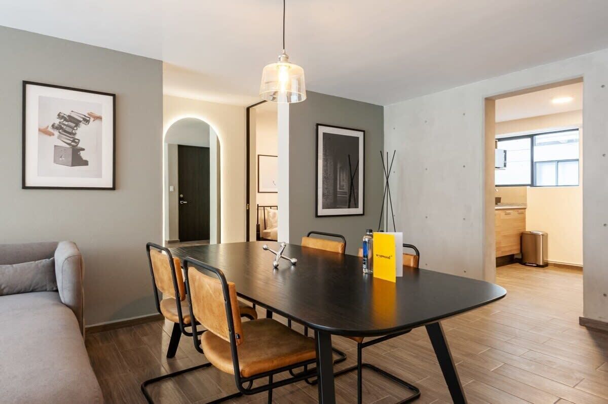Een moderne eetruimte met een grote tafel, stoelen en een hanglamp.