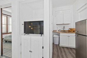 Una cocina moderna con armarios blancos, un refrigerador de acero inoxidable y un televisor integrado.