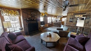 Un interior acogedor y rústico con paredes y techos de madera, una chimenea, asientos cómodos y una zona de bar.