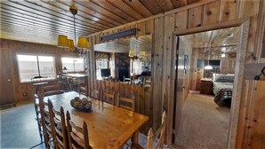 Interior rústico de una cabaña con una mesa de comedor de madera, sillas y una araña.