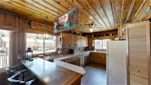 Una cocina rústica con armarios de madera, una barra y un letrero colgante.