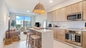 A modern kitchen with a central island, stainless steel appliances, and a large window overlooking a cityscape. - One Bedroom Condo King Bed With City Views (Miami)