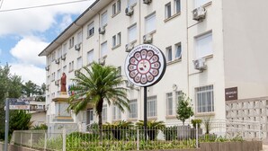 A building with a statue, a sign with a circular emblem, and a reception sign. - Pousada dos Frades (Garibaldi)