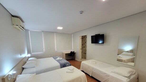 A hotel room with two single beds, a desk, a chair, a television, and a mirror. - Pousada dos Frades (Garibaldi)