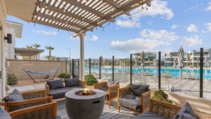 A rooftop patio with outdoor seating, a fire pit, and a view of a swimming pool. - Persian Palms: Desert Color Lagoon + Beaches (St George)