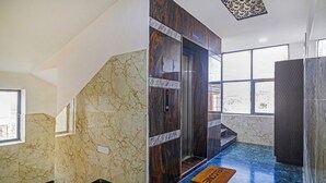 An elevator with a digital display, marble walls, and a blue floor. - Itsy Hotels J A Royal Suites Manikonda (Hyderabad)