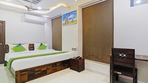 A bedroom with a bed, bedside table, and a wall-mounted air conditioner. - Itsy Hotels J A Royal Suites Manikonda (Hyderabad)