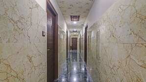 A hallway with marble walls and a polished black floor, leading to a door at the end. - Itsy Hotels J A Royal Suites Manikonda (Hyderabad)