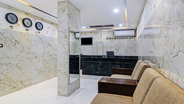 A reception area with marble walls, clocks, and a reception desk. - Itsy Hotels J A Royal Suites Manikonda (Hyderabad)