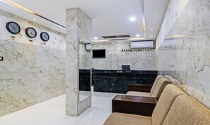 A reception area with marble walls, clocks, and a reception desk. - Itsy Hotels J A Royal Suites Manikonda (Hyderabad)