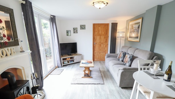 Ein Wohnzimmer mit Sofa, Esstisch, Fernseher und Kamin.