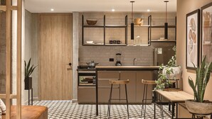 A modern kitchen with a central island, bar stools, and a hanging light fixture. - Mosaic Studios Buenavista (Barranquilla)