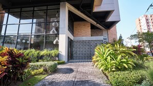 A modern building with large windows, a brick facade, and a well-maintained garden area with various plants. - Mosaic Studios Buenavista (Barranquilla)