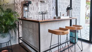 A modern bar area with a stone wall, bar stools, a coffee machine, and a large window. - Mosaic Studios Buenavista (Barranquilla)