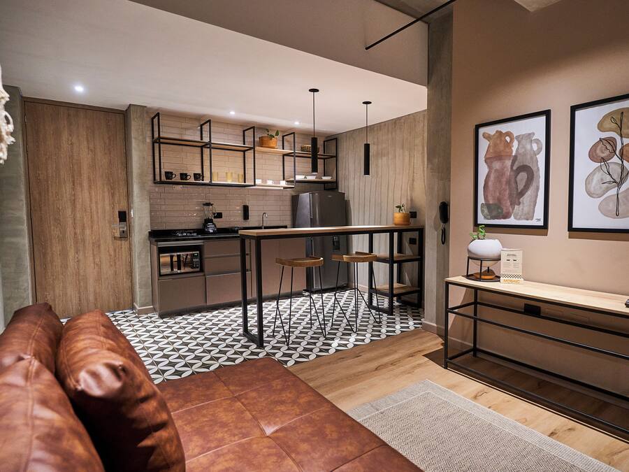 A modern kitchen with a wooden countertop, a built-in oven, and a refrigerator. There are stools and a bench in the dining area.
