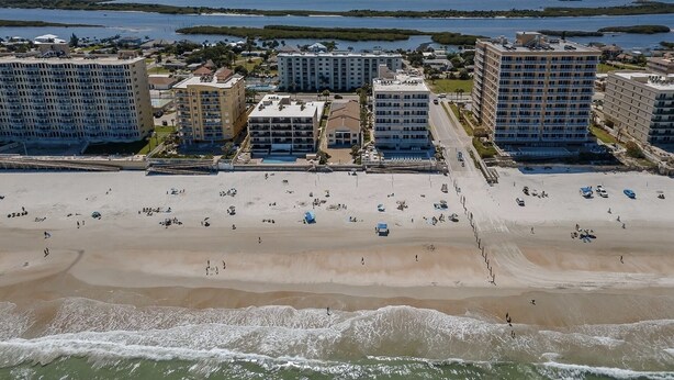 A beachfront hotel with multiple buildings, a sandy beach, and a view of the ocean. - Gorgeous Condo Steps From the Beach! (Daytona Beach Shores)