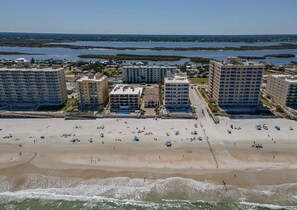 Ein Strandhotel mit mehreren Gebäuden, einem Sandstrand und Blick auf den Ozean.