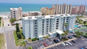 A multi-story hotel with a parking lot and a view of the beach. - Gorgeous Condo Steps From the Beach! (Daytona Beach Shores)