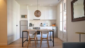 Eine moderne Küche mit weißen Schränken, einer eingebauten Mikrowelle, einem Edelstahlkühlschrank und einem Essbereich mit einem Holztisch und Stühlen.