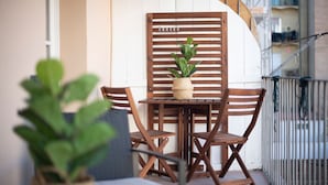 Ein Holz-Sitzbereich im Freien mit Tisch und Stühlen, einem Blumentopf und einem weißen Geländer.
