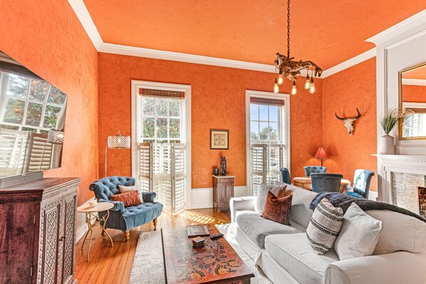 Ein Wohnzimmer mit orangefarbenen Wänden, einem Kamin, einer Kristallleuchtre und einer Dekoration aus einem Kuhschädel.