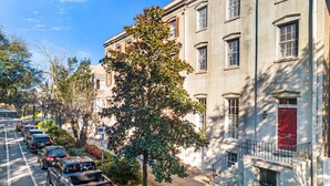 Une rue bordée de voitures garées, avec un arbre au premier plan.
