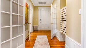 Un couloir avec un plancher en bois, des portes blanches et un mur blanc avec une porte au fond.