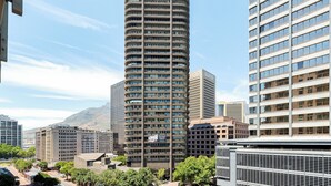 Un edificio alto y cilíndrico de diseño moderno, rodeado de otros edificios altos y árboles.