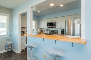 A modern kitchen with white cabinets, stainless steel appliances, and a wooden countertop.