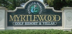 Une enseigne pour le Myrtlewood Golf Resort & Villas, avec un logo au-dessus du nom.