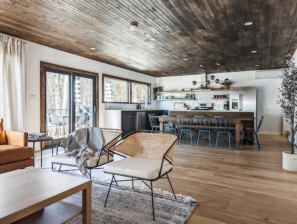 Un interior moderno con comedor, cocina y ventanas amplias.