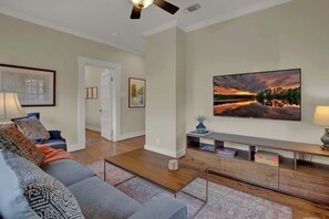 A living room with a sofa, coffee table, and a flat-screen TV on a stand.