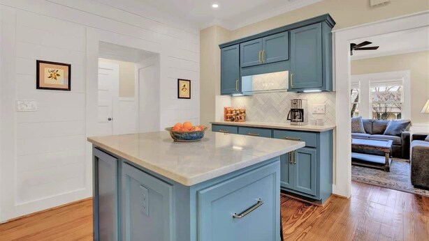 A kitchen with blue cabinets, a marble countertop, and a bowl of fruit.