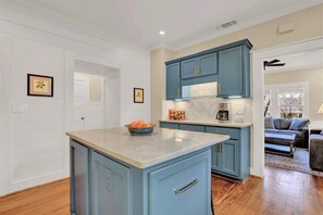 A kitchen with blue cabinets, a marble countertop, and a bowl of fruit.