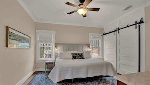 A bedroom with a bed, a ceiling fan, a window, and a sliding door.