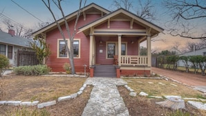 A red house with a front porch, a stone pathway, and a mailbox.