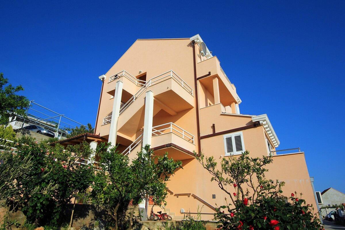 A multi-story building with balconies and a satellite dish.