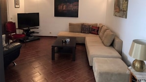 A living room with a sofa, a coffee table, a TV, and a red chair. - Apartments Anita (Konavle)