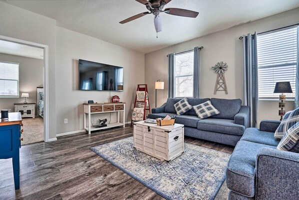 A living room with a grey sofa, a coffee table, a TV, and a ceiling fan. - Dreamy Windsor Home with Grill ~ 3 Miles to Lake! (Windsor)
