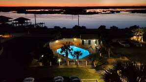 Ein Haus mit Swimmingpool, umgeben von einem eingezäunten Garten und Palmen.