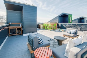 A rooftop patio with outdoor seating, including a sofa, chairs, and a table.