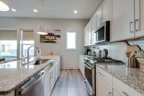 Una cocina moderna con encimeras de granito, electrodomésticos de acero inoxidable y armarios blancos.