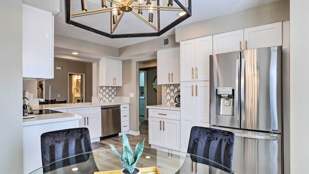 A modern kitchen with white cabinets, a stainless steel refrigerator, and a glass dining table with chairs. - Chic Palm Desert Condo w/ Resort-Style Amenities! (Palm Desert)