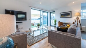 Un salon moderne avec un canapé, une table basse en verre, une lampe et un téléviseur fixé au mur.