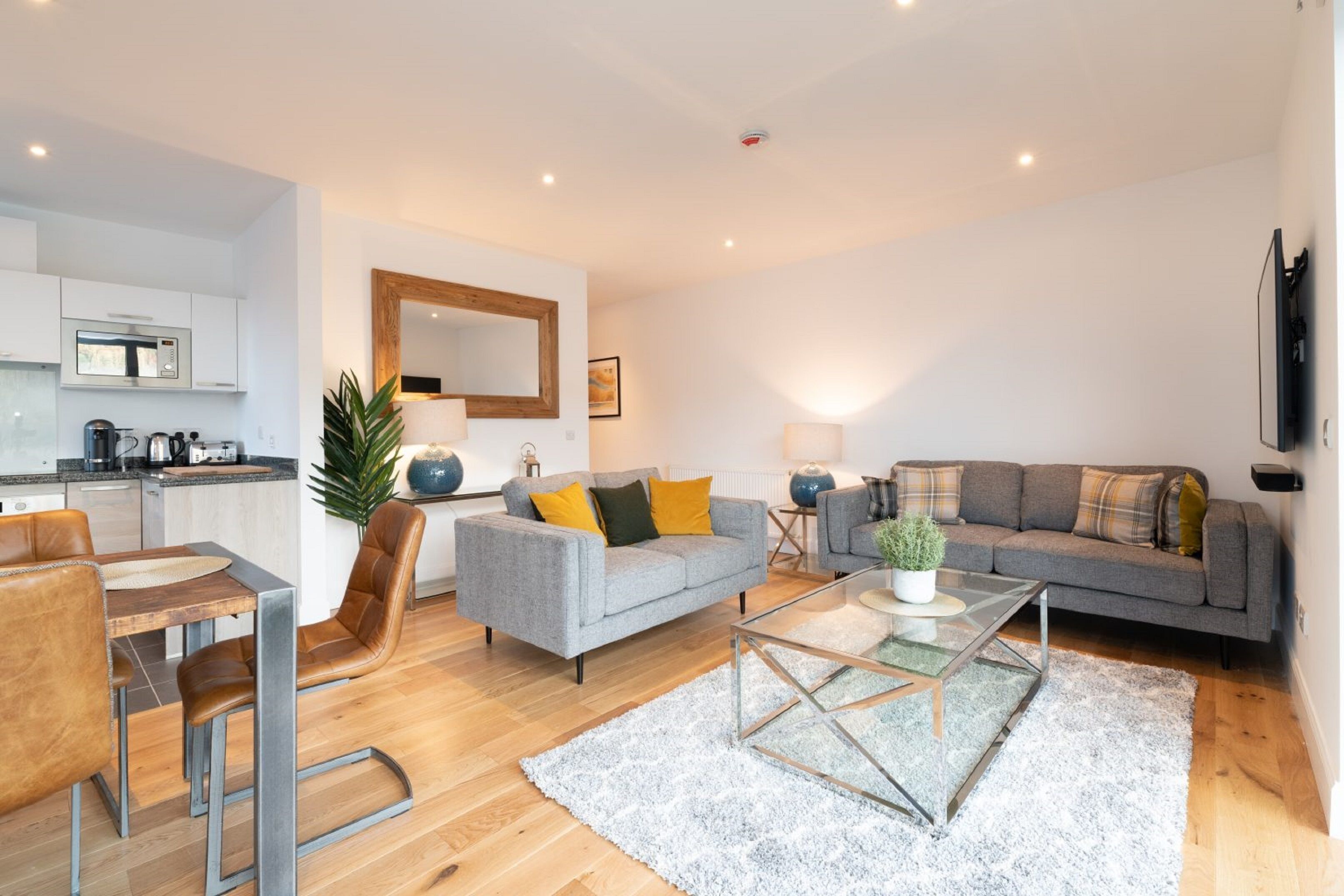 A modern living room with a grey sofa, a coffee table, and a dining area with a wooden table and chairs.