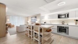 A modern kitchen with white cabinetry, a central island, and built-in appliances.