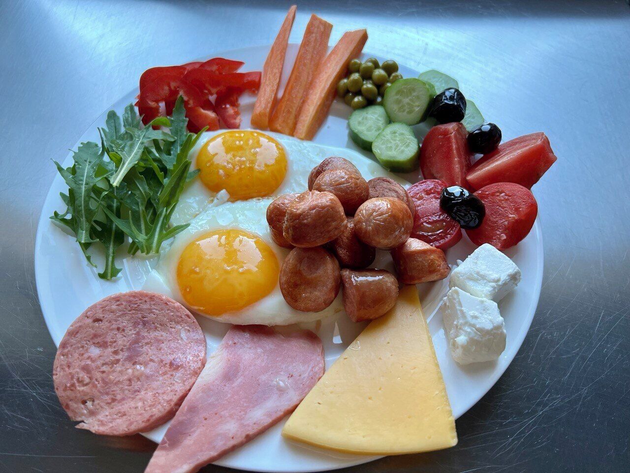 A plate of assorted food items including eggs, sausages, cheese, and vegetables.