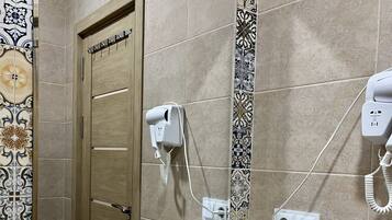 A bathroom with a sink, mirror, and towel rack. There are toiletries and a shaving kit on the counter.